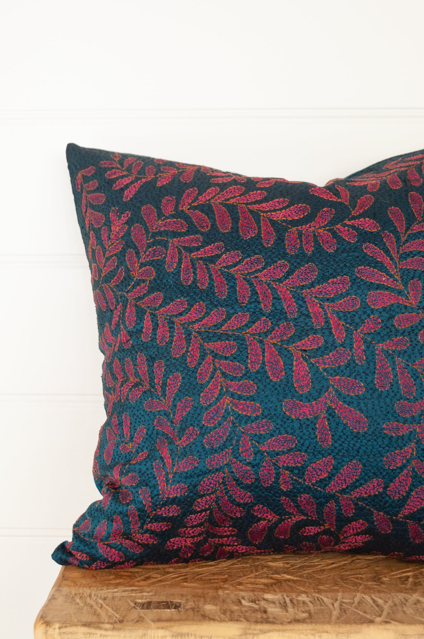 BKantha stitched on vintage silk, this square cushion features an allover tracery of vine leaves in cherry red on a black stitched teal blue background.