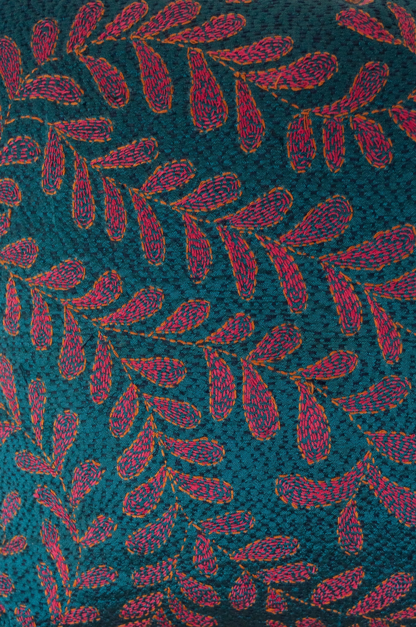 BKantha stitched on vintage silk, this square cushion features an allover tracery of vine leaves in cherry red on a black stitched teal blue background.