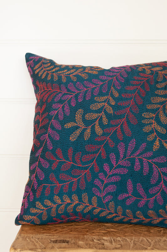 Kantha stitched on vintage silk, this square cushion features an allover tracery of vine leaves in cherry red, rose pink and apricot on a black stitched teal blue background