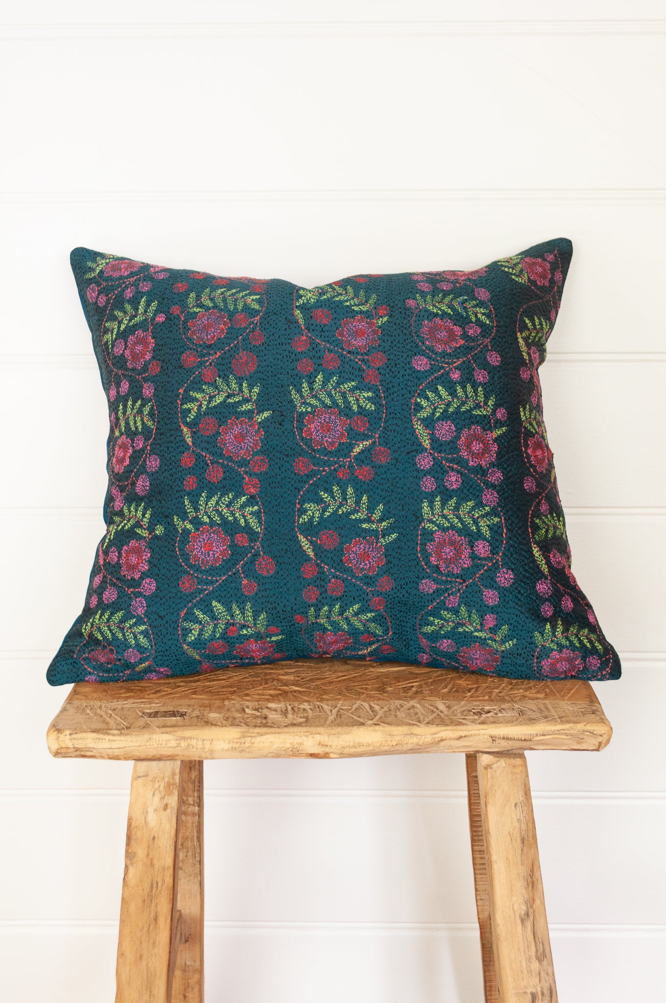 Kantha stitched on vintage silk, this square cushion features panels of floral sprays in cherry red and rose pink, with lime green leaves, on a black stitched teal blue background.