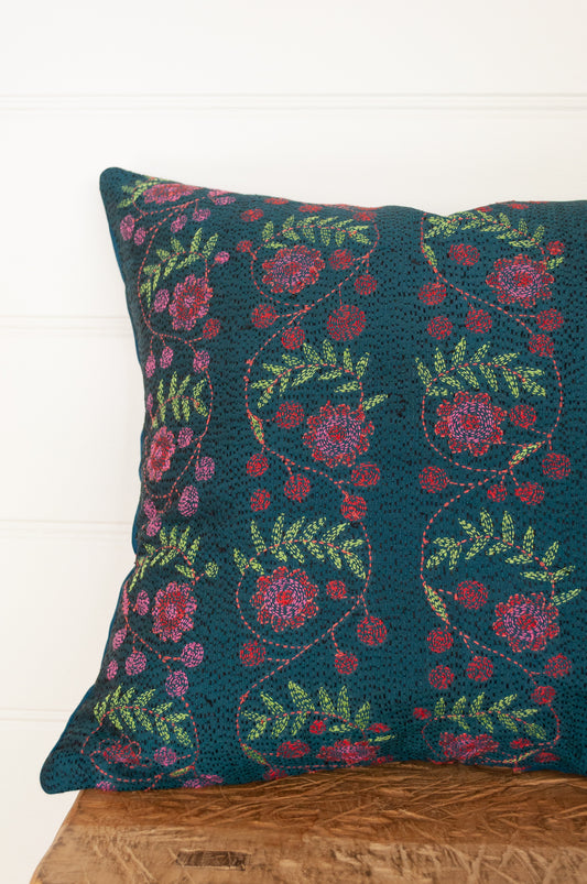 Kantha stitched on vintage silk, this square cushion features panels of floral sprays in cherry red and rose pink, with lime green leaves, on a black stitched teal blue background.