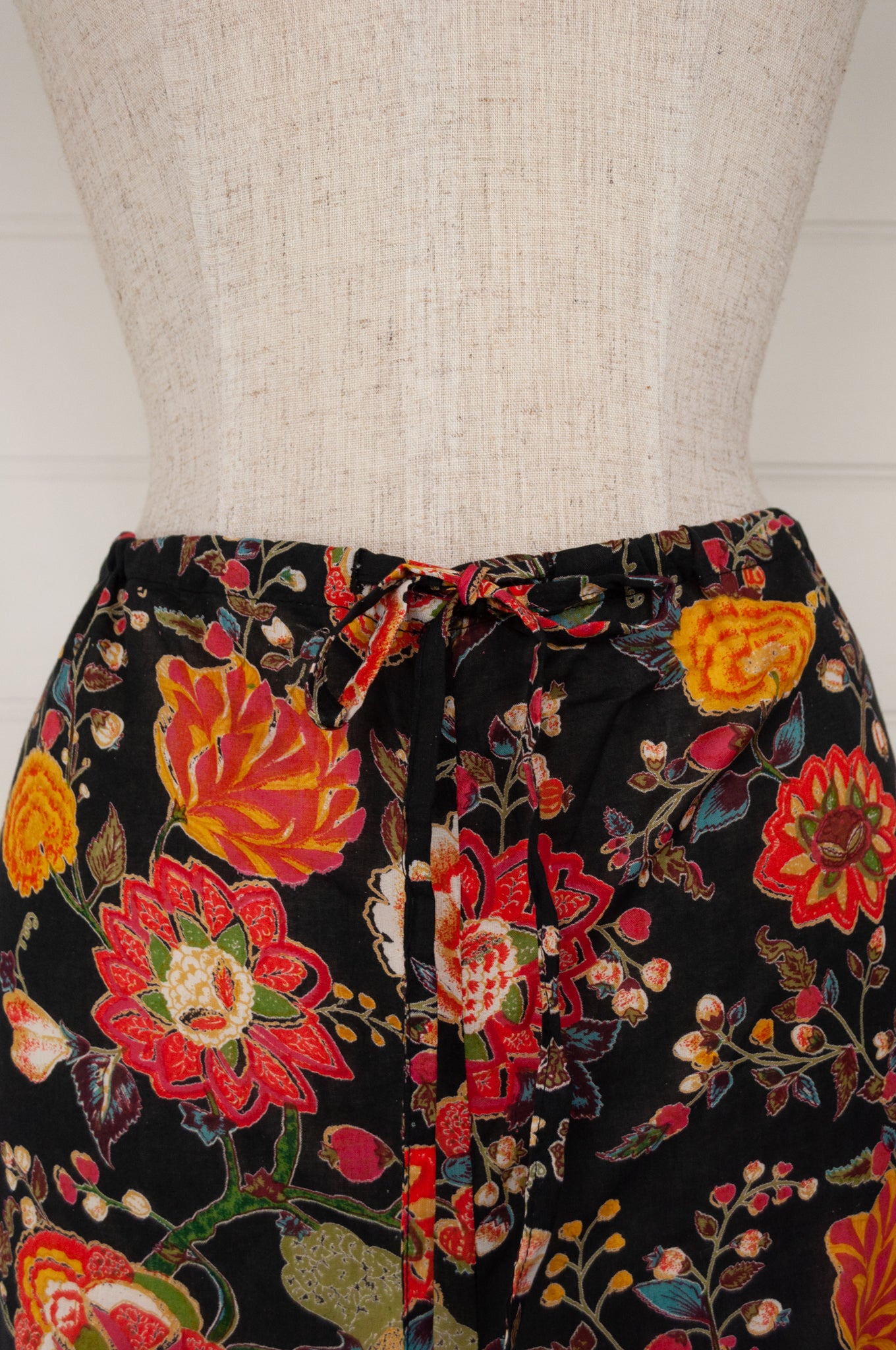 Ethically made cotton voile pyjamas, tropical print of red, gold and orange flowers on black background.