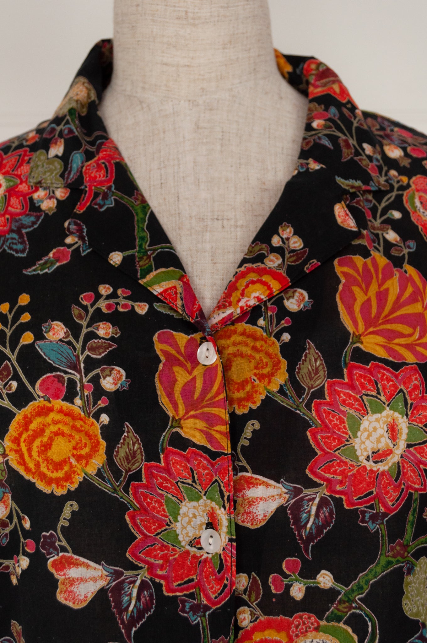 Ethically made cotton voile pyjamas, tropical print of red, gold and orange flowers on black background.