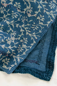 Vintage kantha quilt blockprinted with mud resist in natural indigo, vines and flowers in white on blue, sari edging and coloured embroidery
