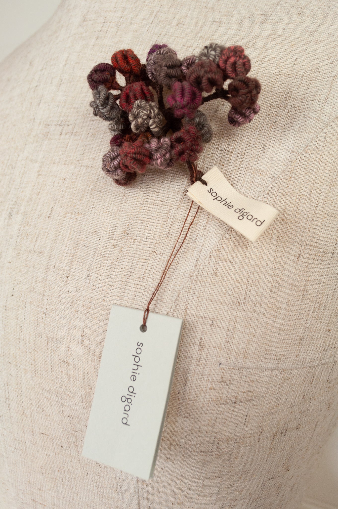 Sophie Digard TINYV2 wool embroidered flower brooch in chocolate, pink,grey and red tones.