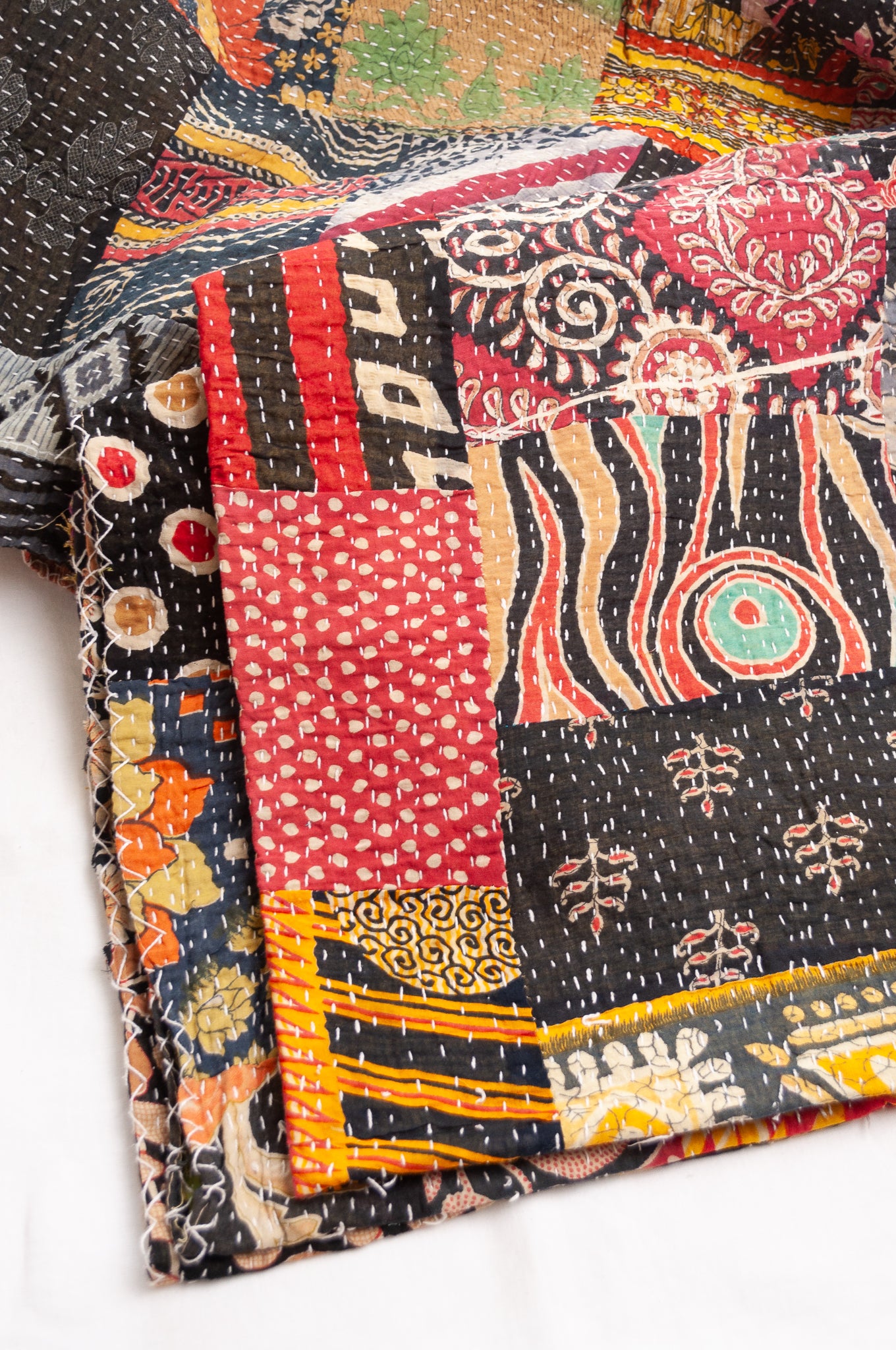 Vintage patchwork kantha quilt im multiple prints with black base.