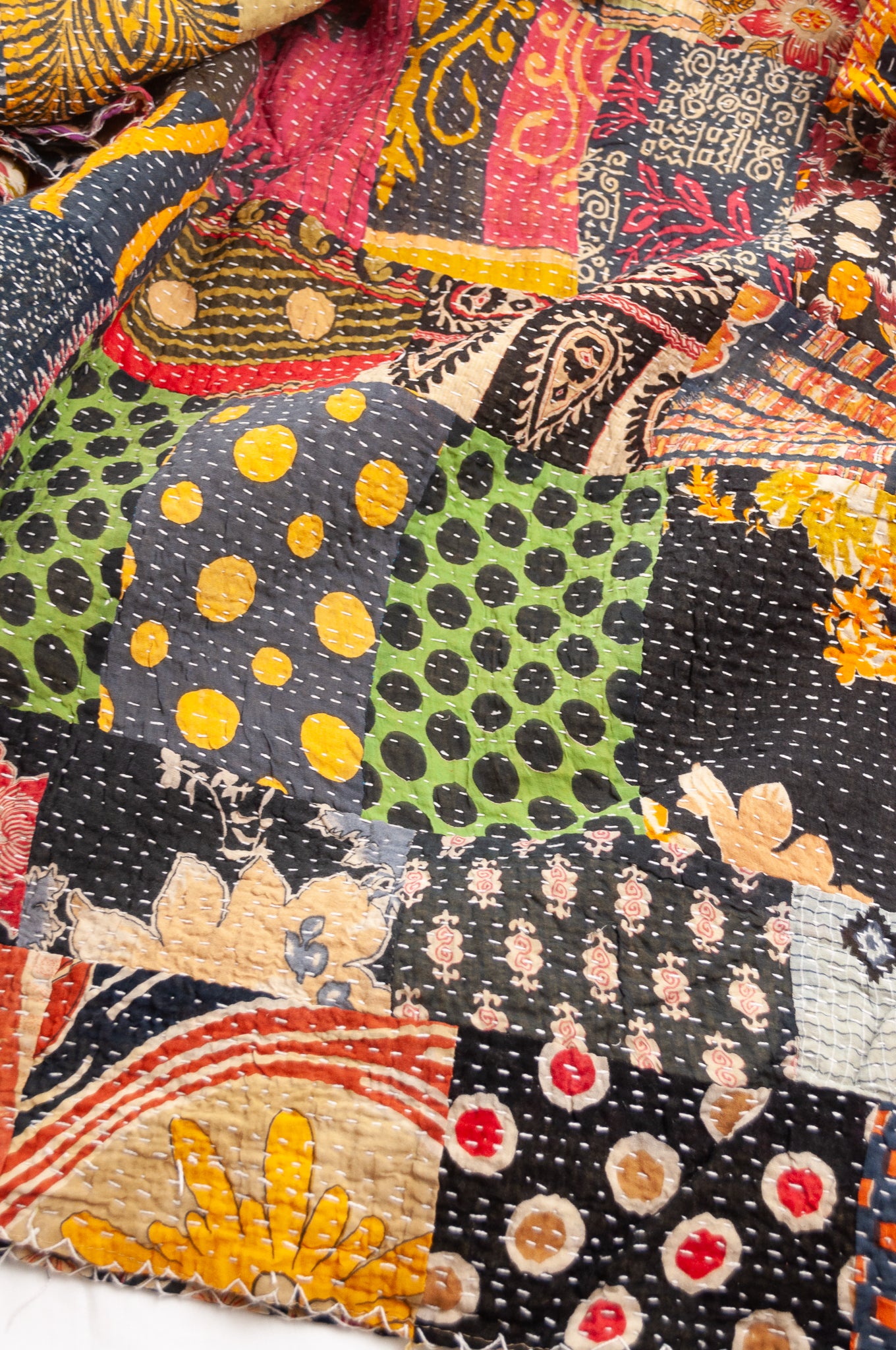Vintage patchwork kantha quilt im multiple prints with black base.