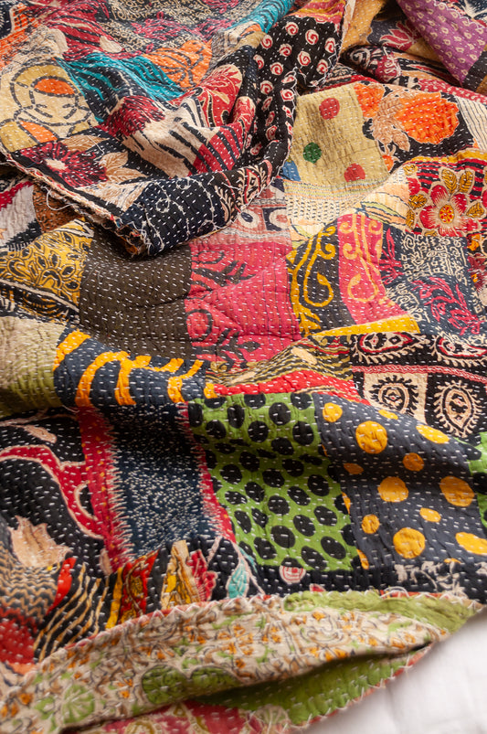 Vintage patchwork kantha quilt im multiple prints with black base.