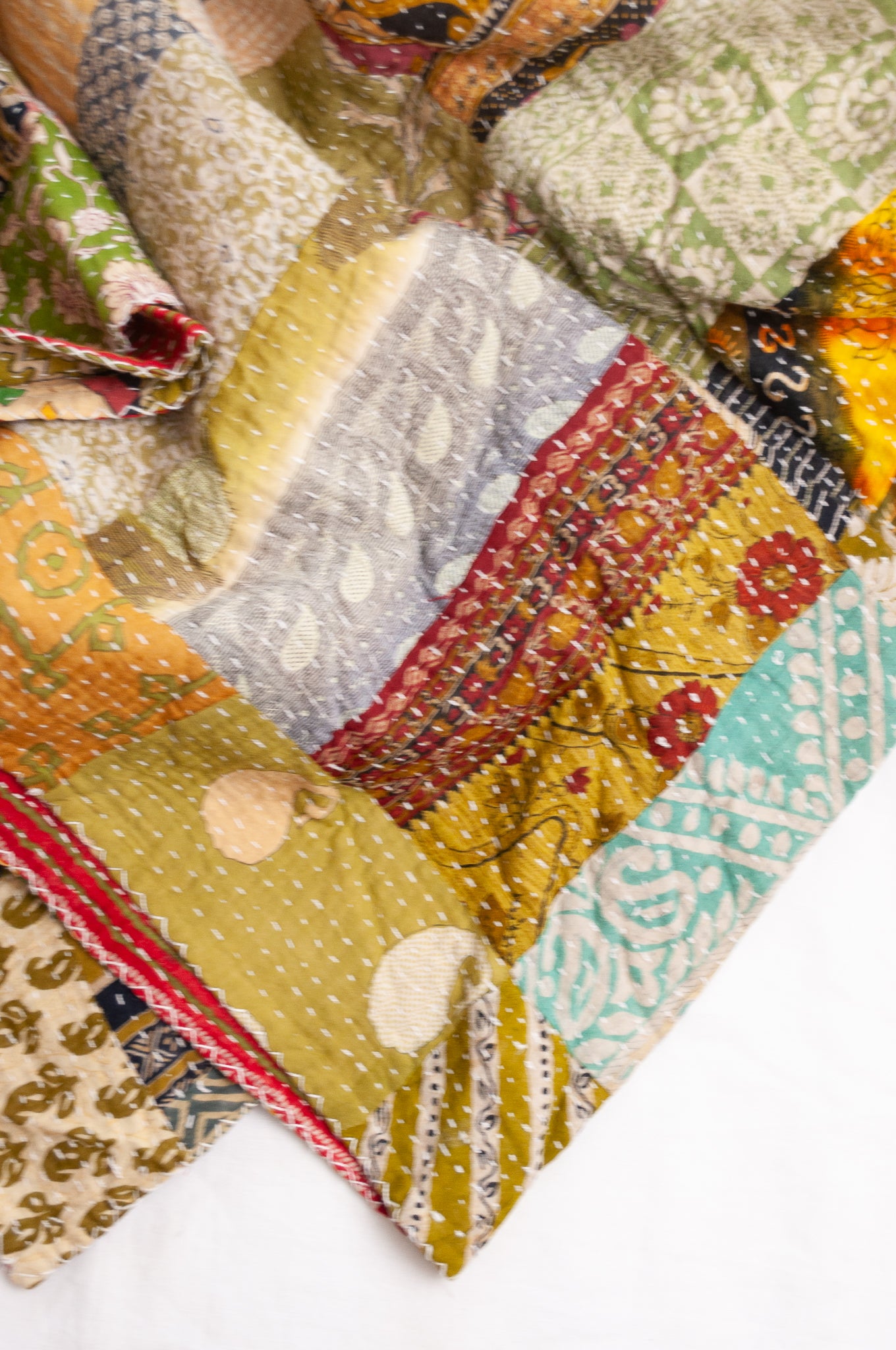 Vintage patchwork kantha quilt in multiple prints with green base.