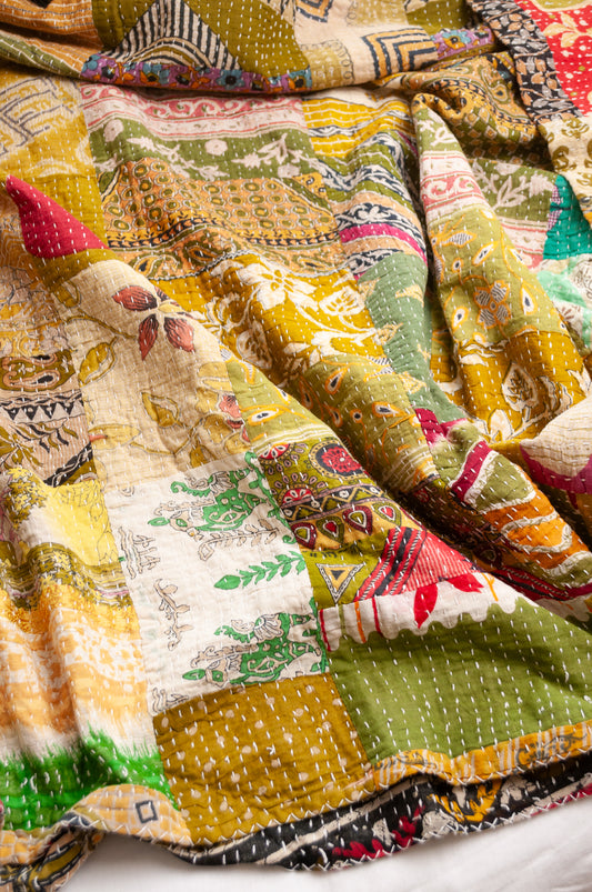 Vintage patchwork kantha quilt in multiple prints with green base.