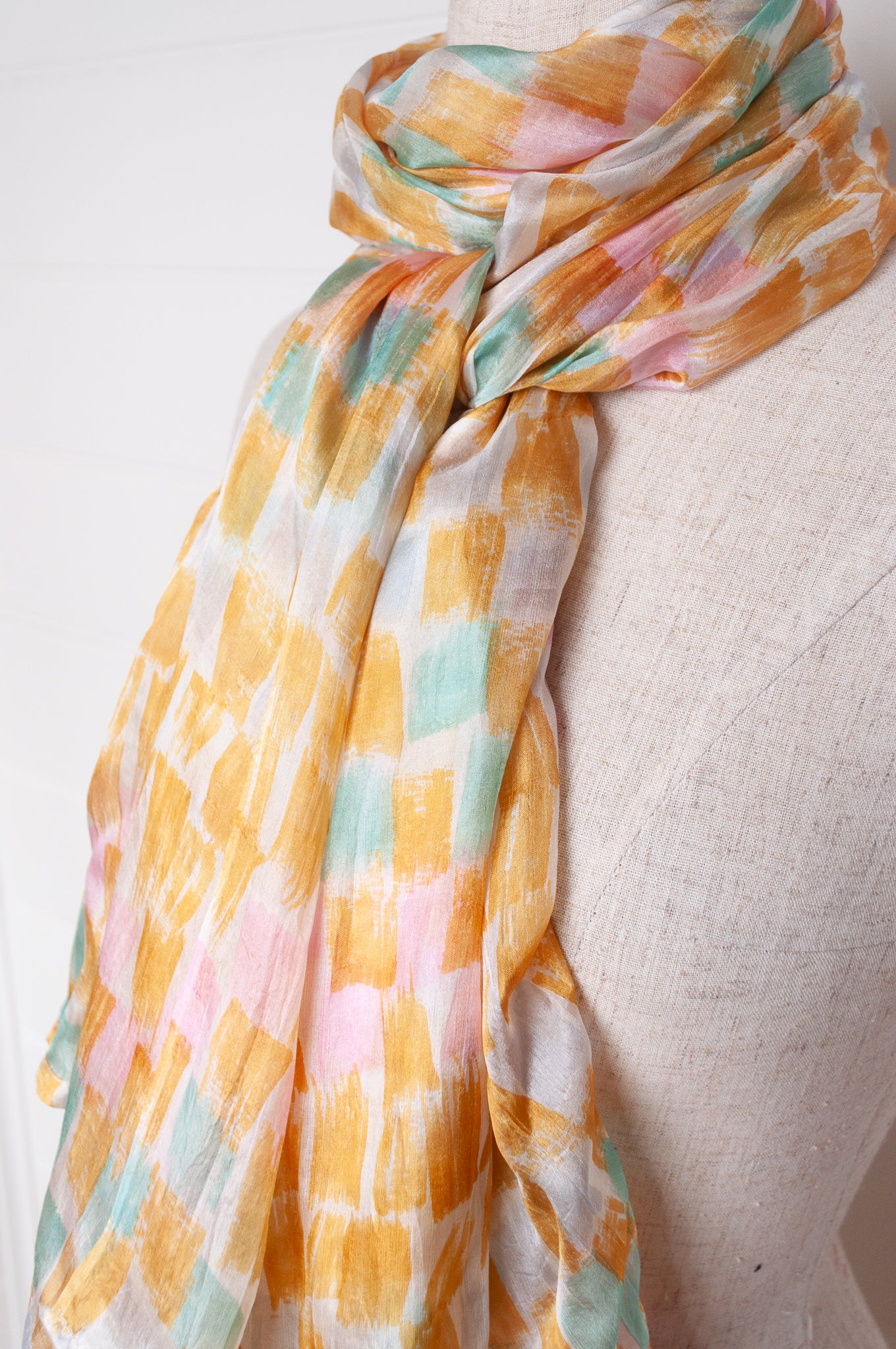 Hand painted pure silk scarf with light mustard pink and aqua blue brushstrokes on white.