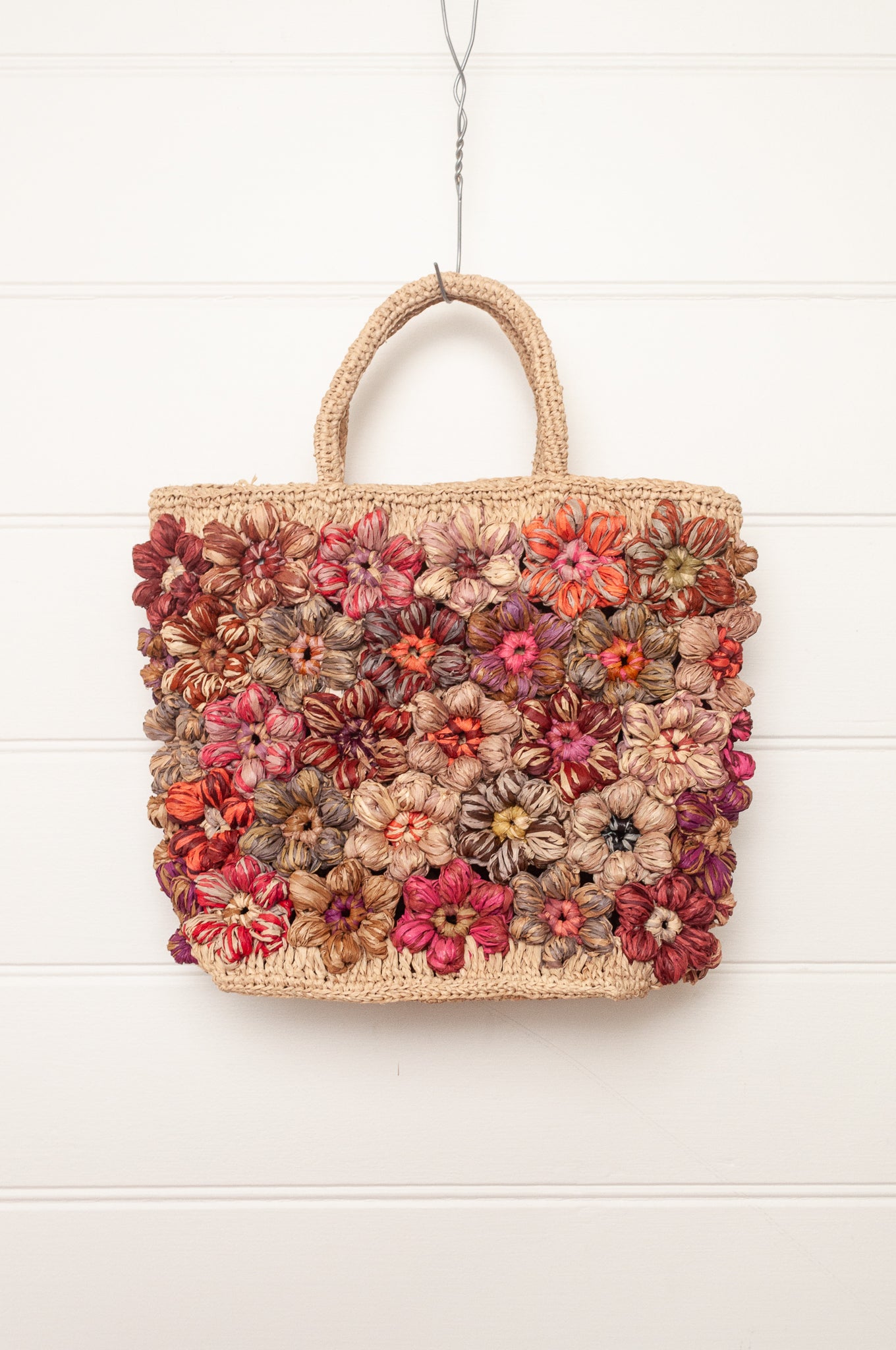 Sophie Digard natural raffia crocheted bag with all over flowers in reds and pinks.
