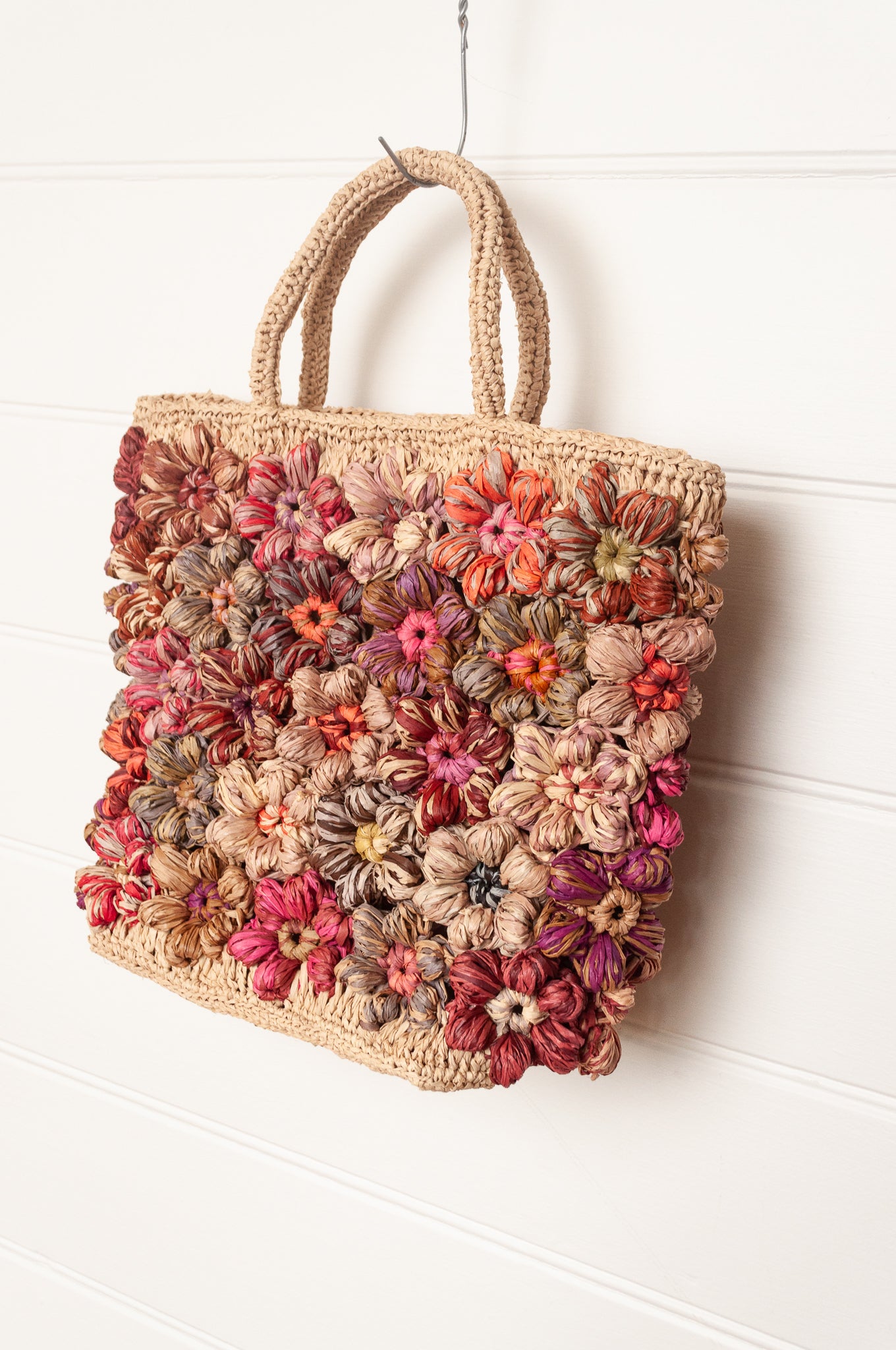 Sophie Digard natural raffia crocheted bag with all over flowers in reds and pinks.