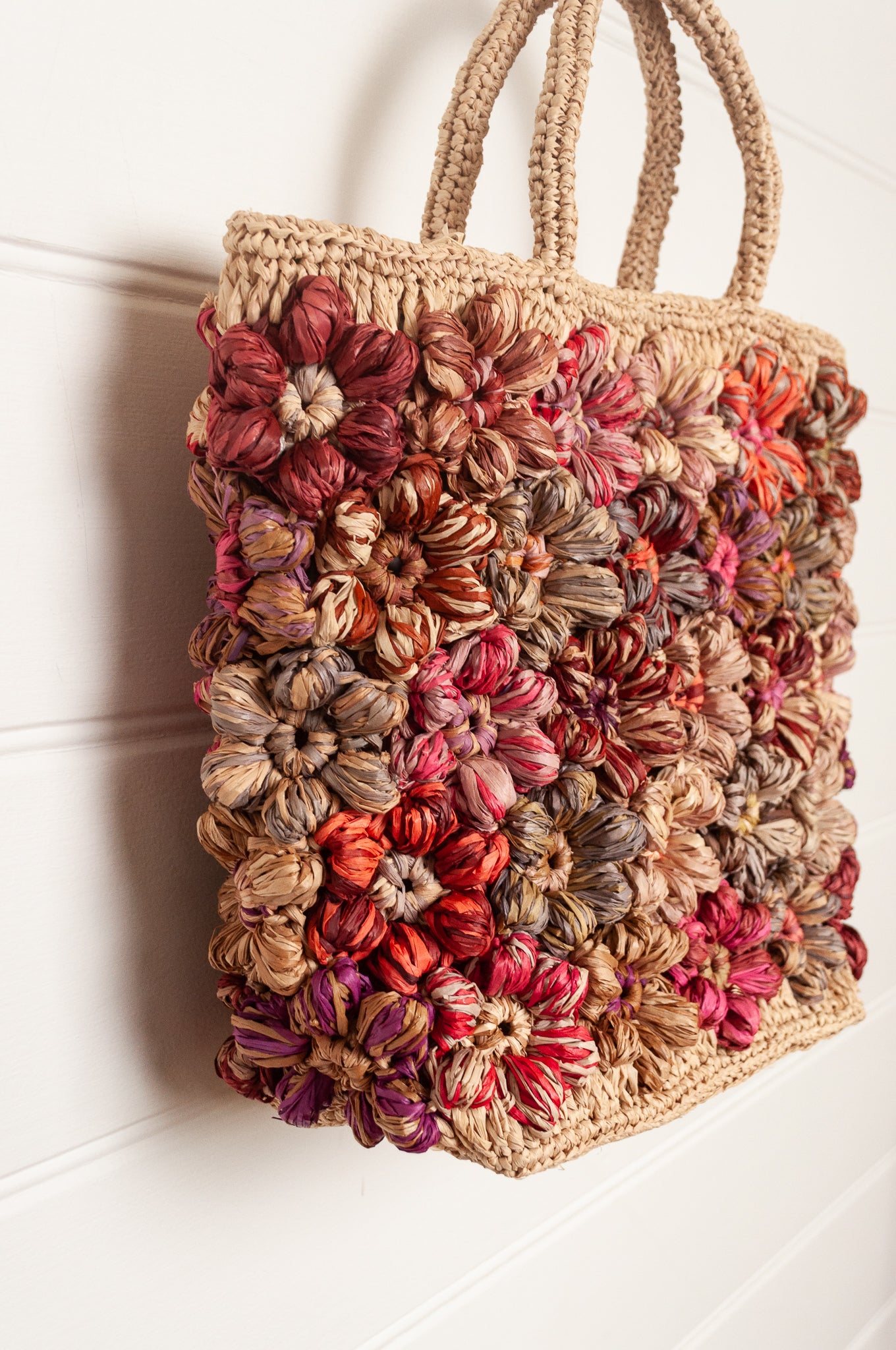Sophie Digard natural raffia crocheted bag with all over flowers in reds and pinks.