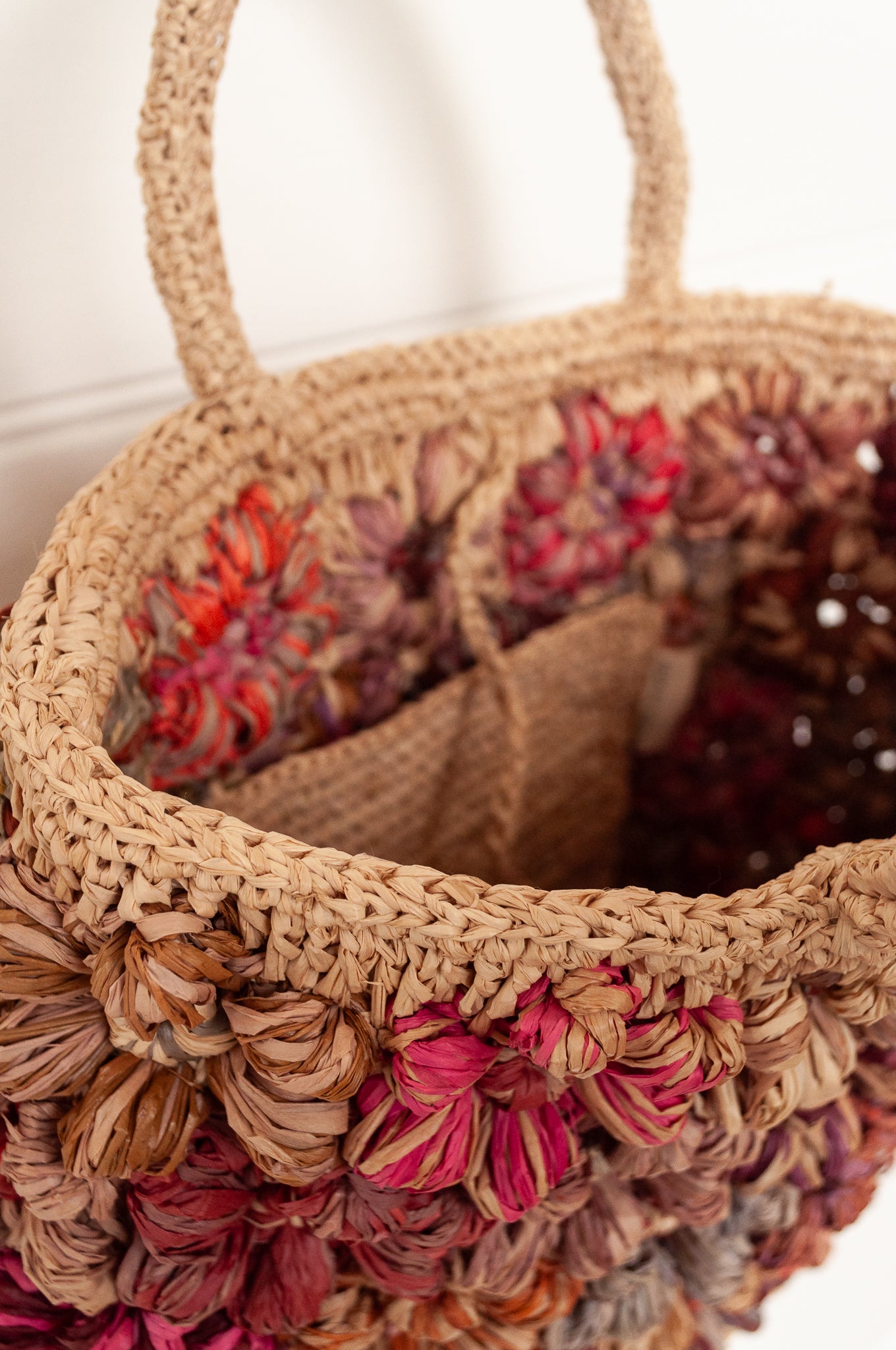 Sophie Digard natural raffia crocheted bag with all over flowers in reds and pinks.