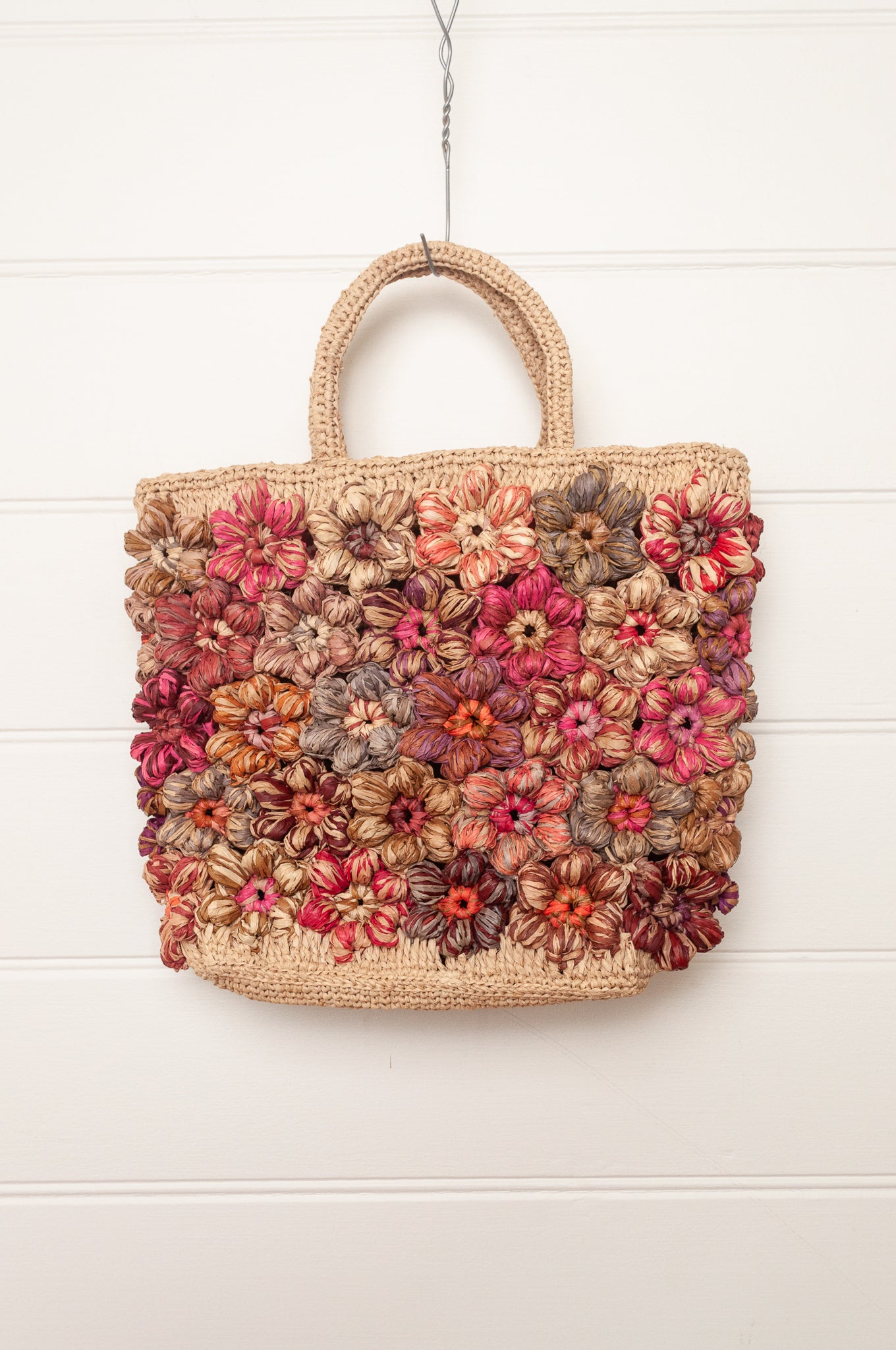 Sophie Digard natural raffia crocheted bag with all over flowers in reds and pinks.