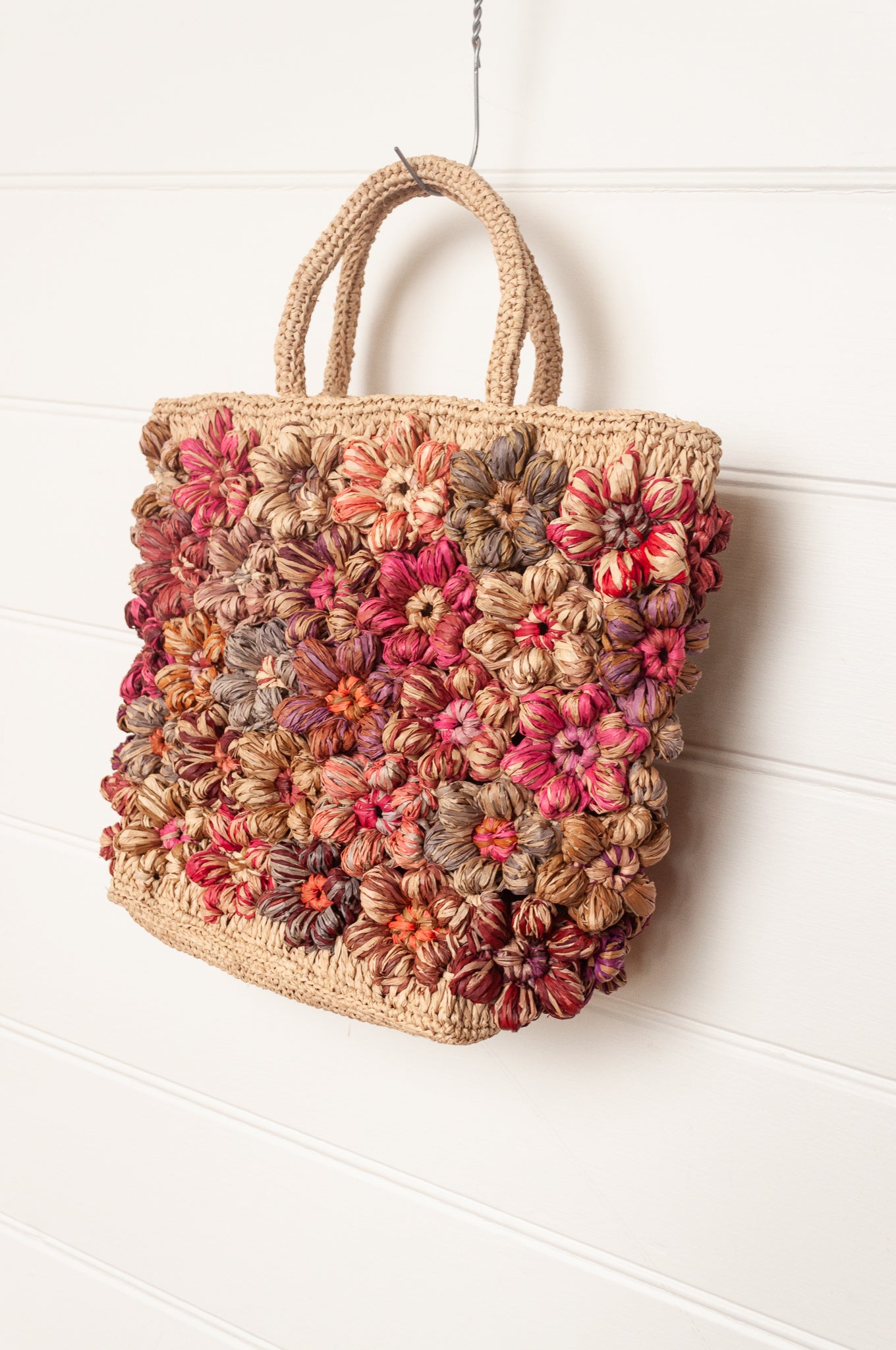 Sophie Digard natural raffia crocheted bag with all over flowers in reds and pinks.