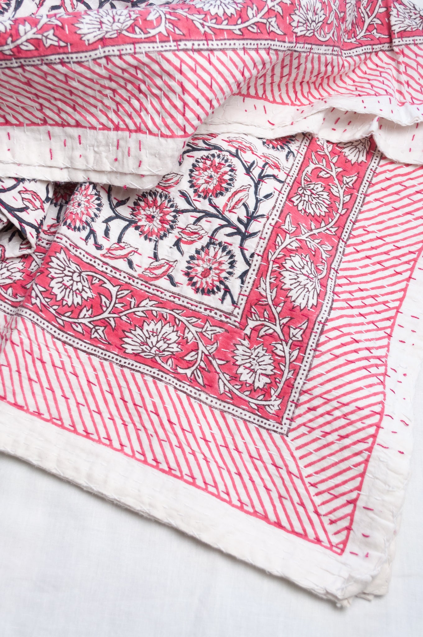 Cotton kantha quilt in raspberry pink floral on white.