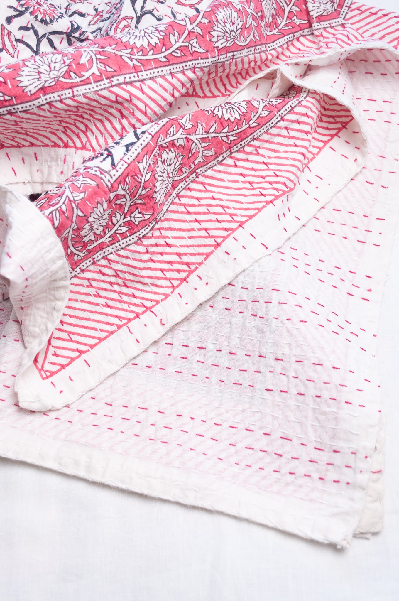Cotton kantha quilt in raspberry pink floral on white.