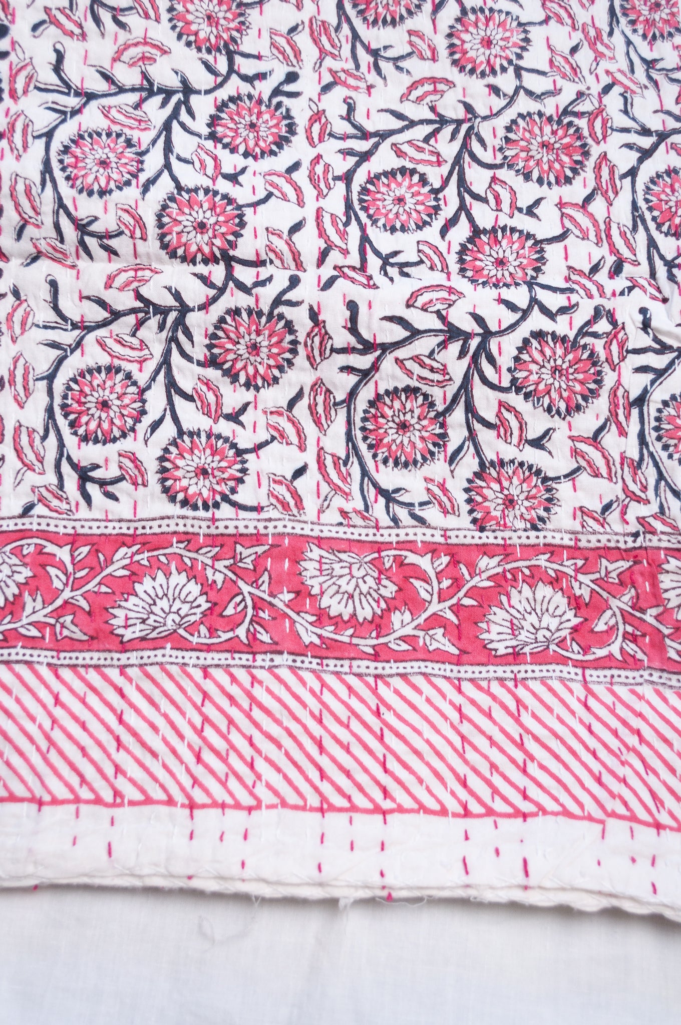 Cotton kantha quilt in raspberry pink floral on white.