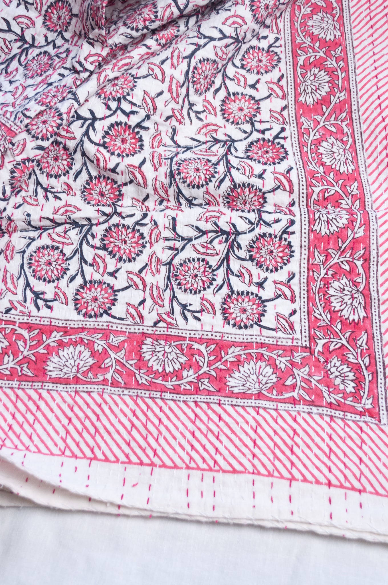Cotton kantha quilt in raspberry pink floral on white.