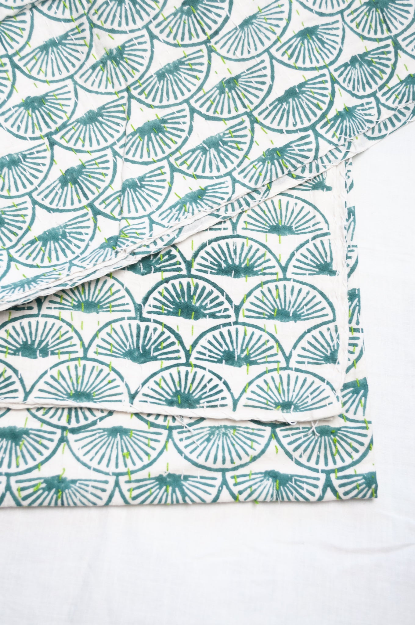 Cotton kantha quilt in teal green fans on white.