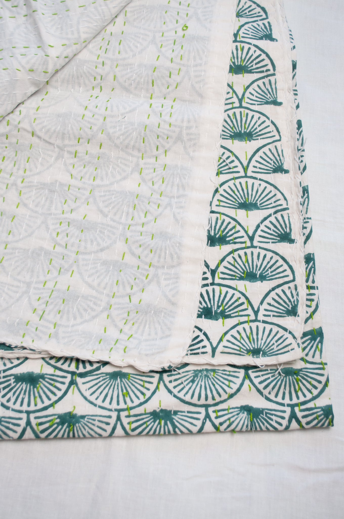 Cotton kantha quilt in teal green fans on white.
