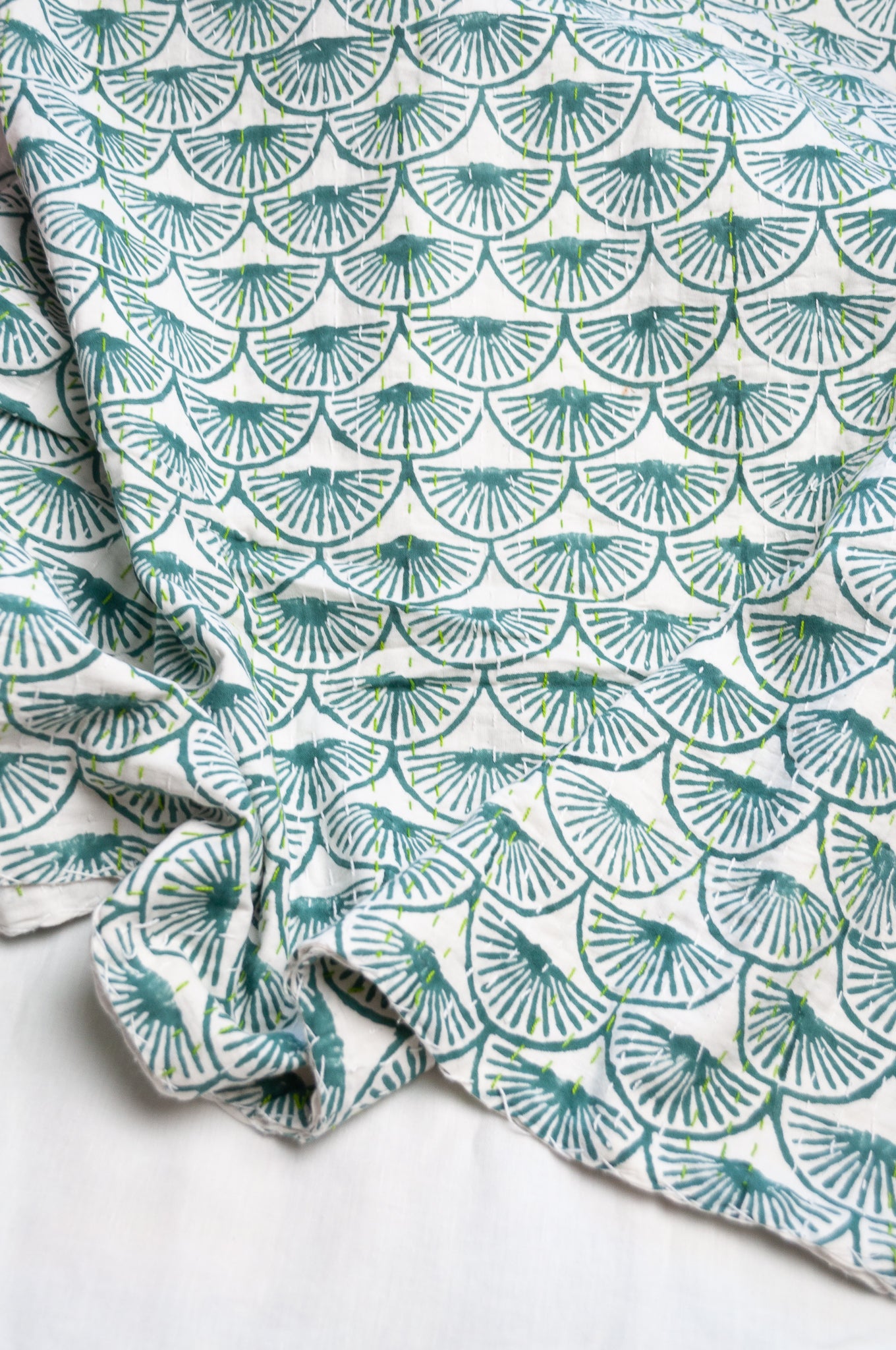 Cotton kantha quilt in teal green fans on white.