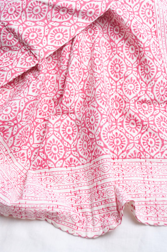 Cotton kantha quilt with an abstract floral design in pink on white.