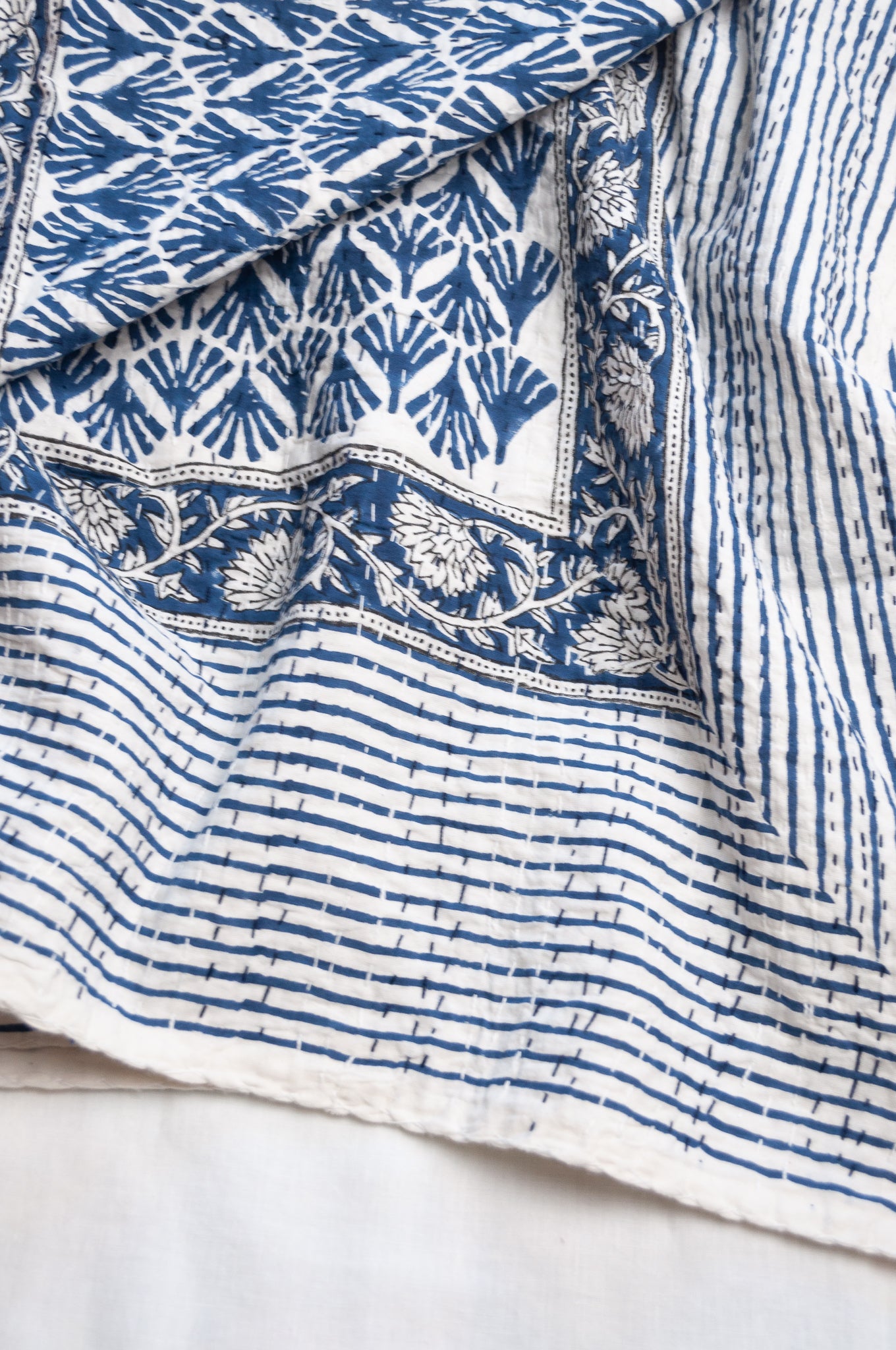 Indigo fan and floral on white cotton kantha quilt.