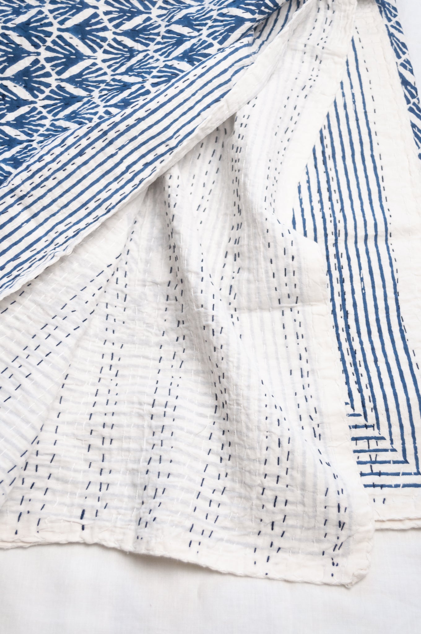 Indigo fan and floral on white cotton kantha quilt.