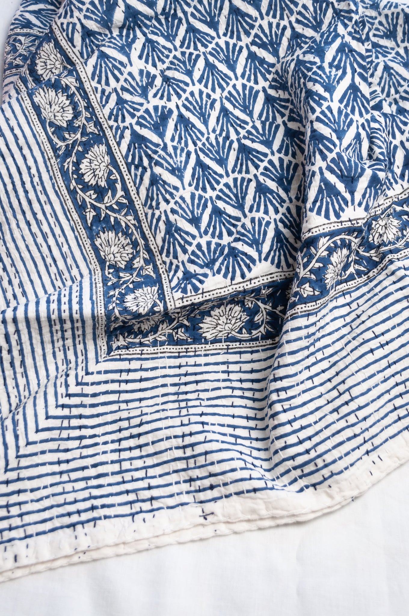 Indigo fan and floral on white cotton kantha quilt.