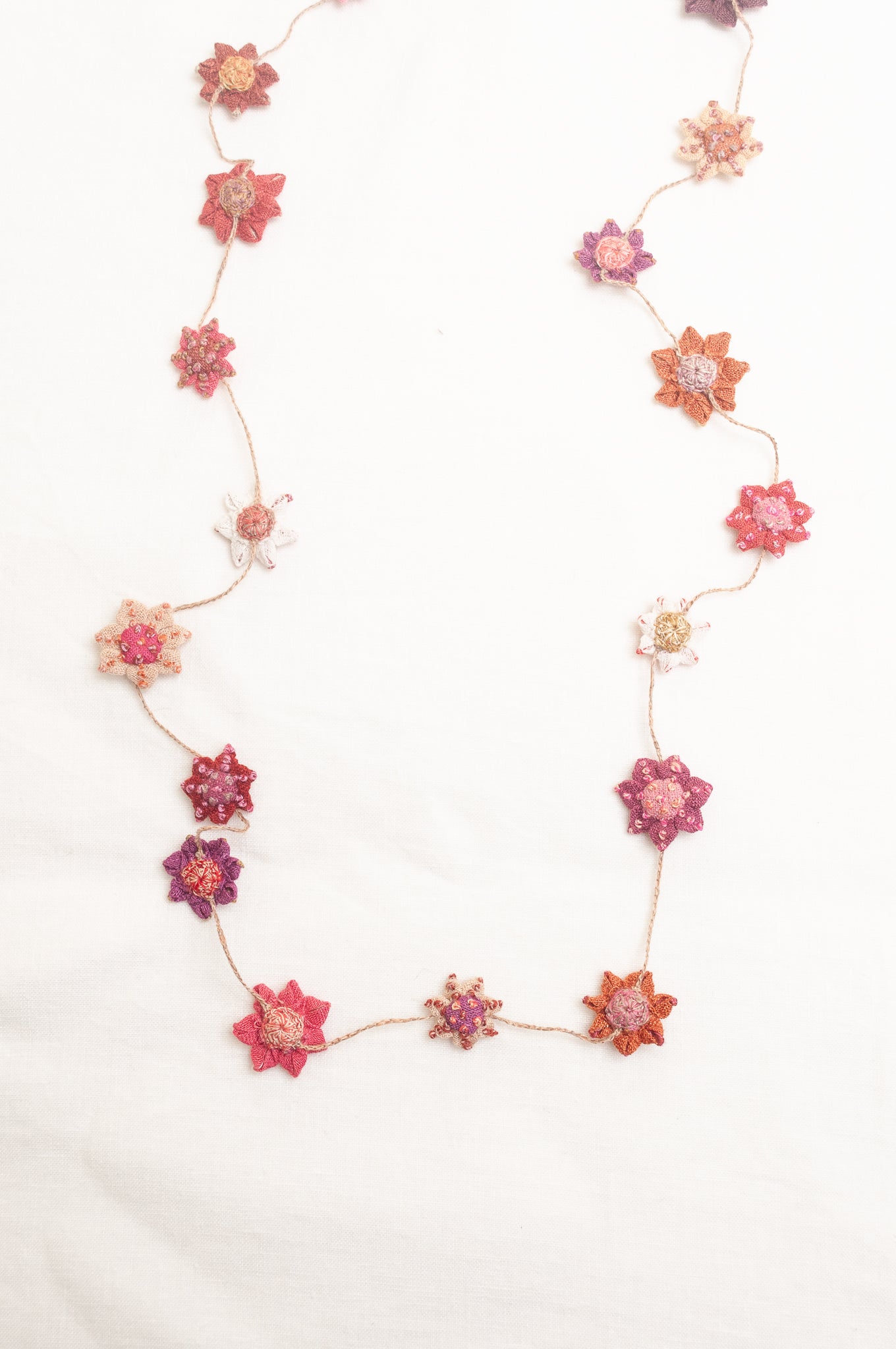 Sophie Digard star flower embroidered linen necklace in pinks and reds.