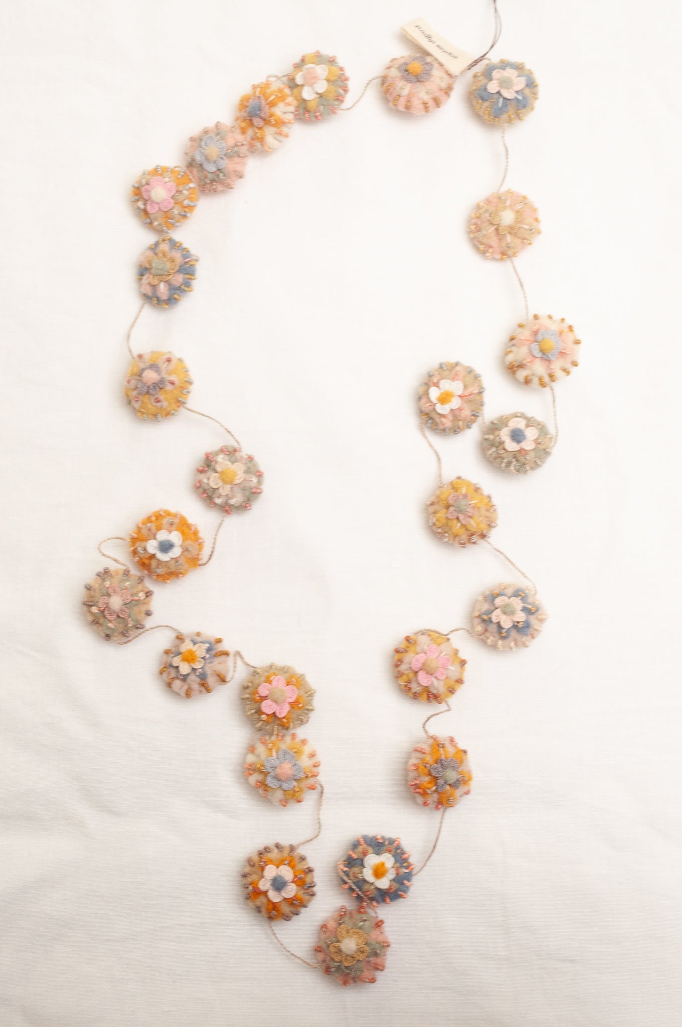 Sophie Digard necklace of linen medallions with flower embroidery.