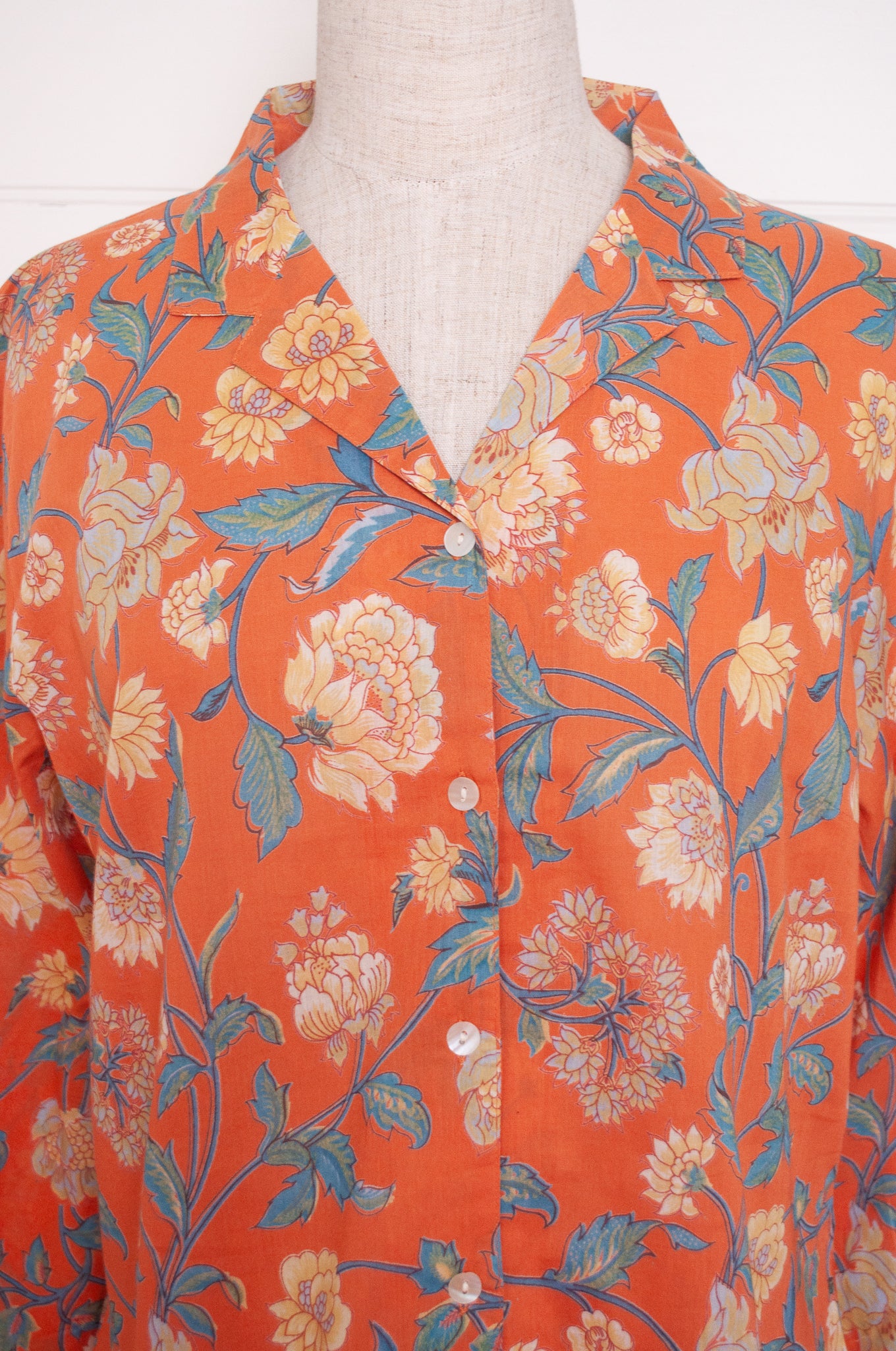 Juniper Hearth pyjama set in Kashmir saffrron, vanilla flowers on orange background.