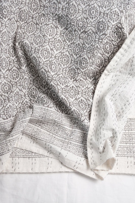 Cotton kantha quilt with an abstract floral design in silver grey on white.
