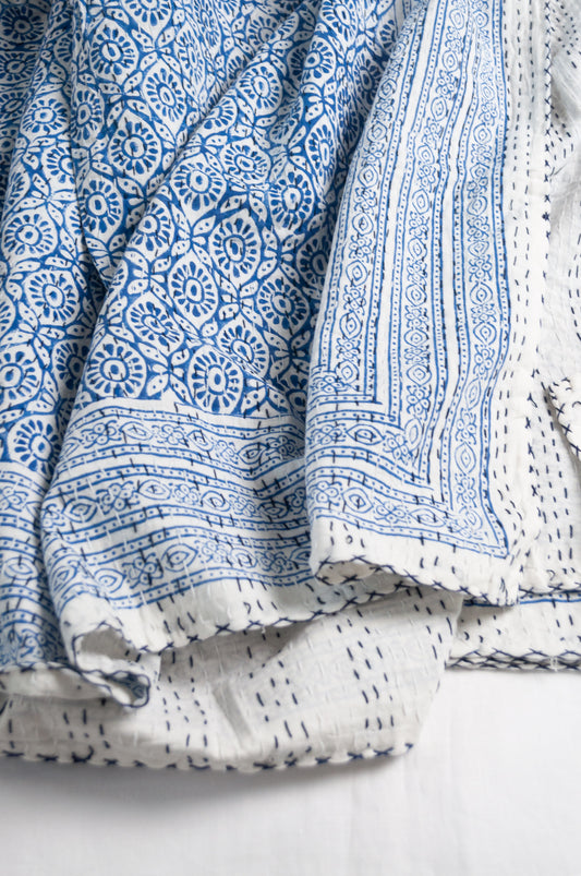 Cotton kantha quilt with an abstract floral design in blue on white.