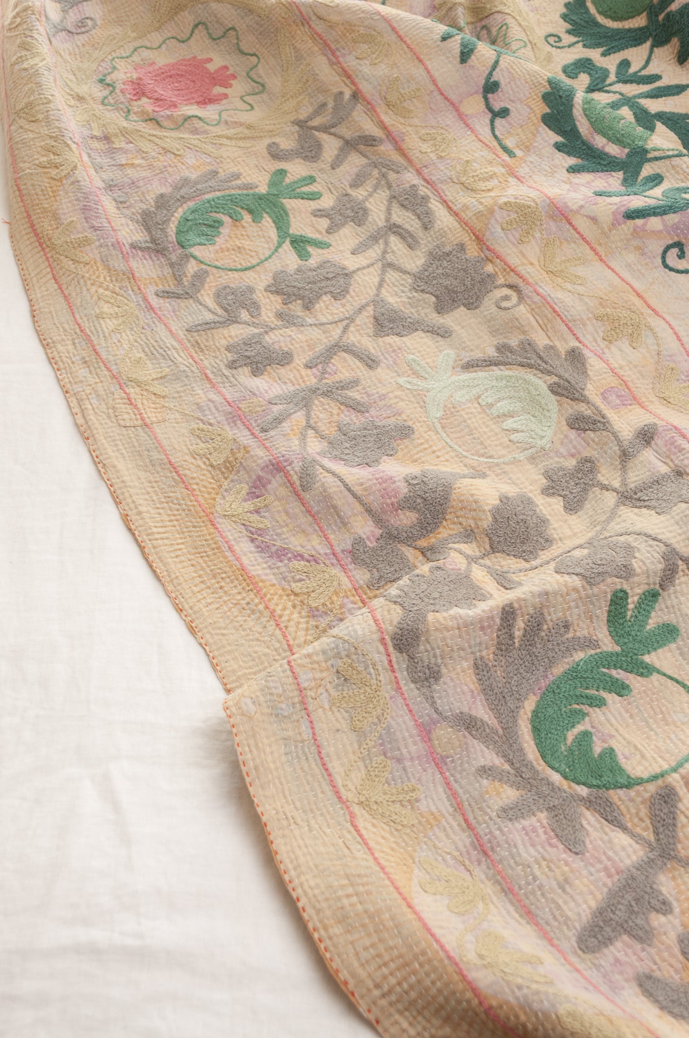 Vintage kantha quilt embroidered Suzani style floral design in teal and pink on pastel floral stripes.