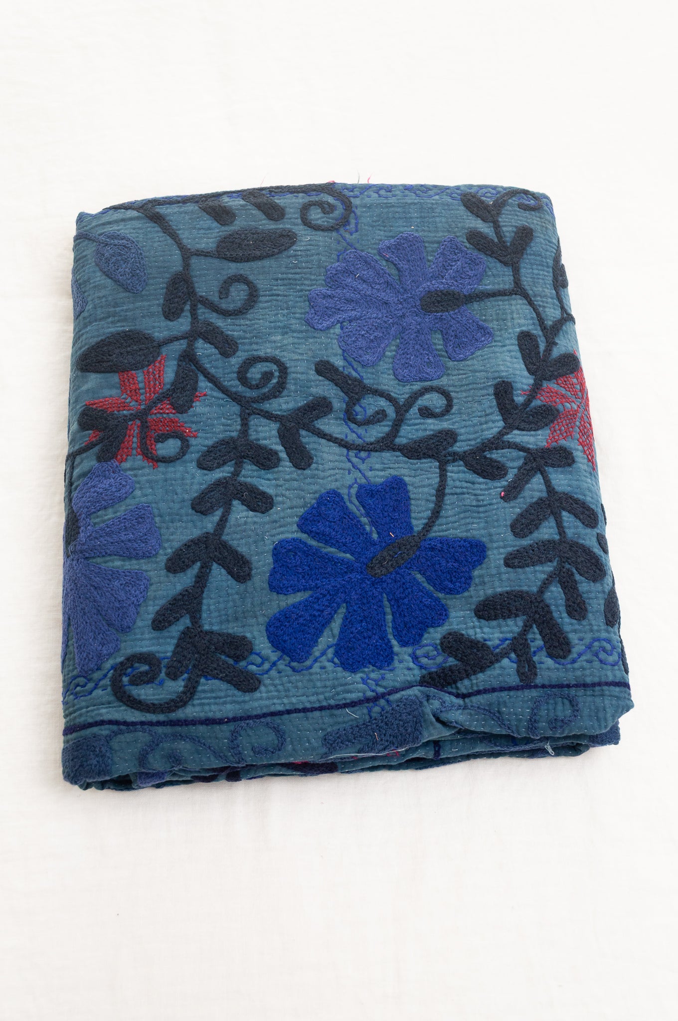 Vintage indigo kantha quilt embroidered Suzani style in shades of indigo with red highlights.