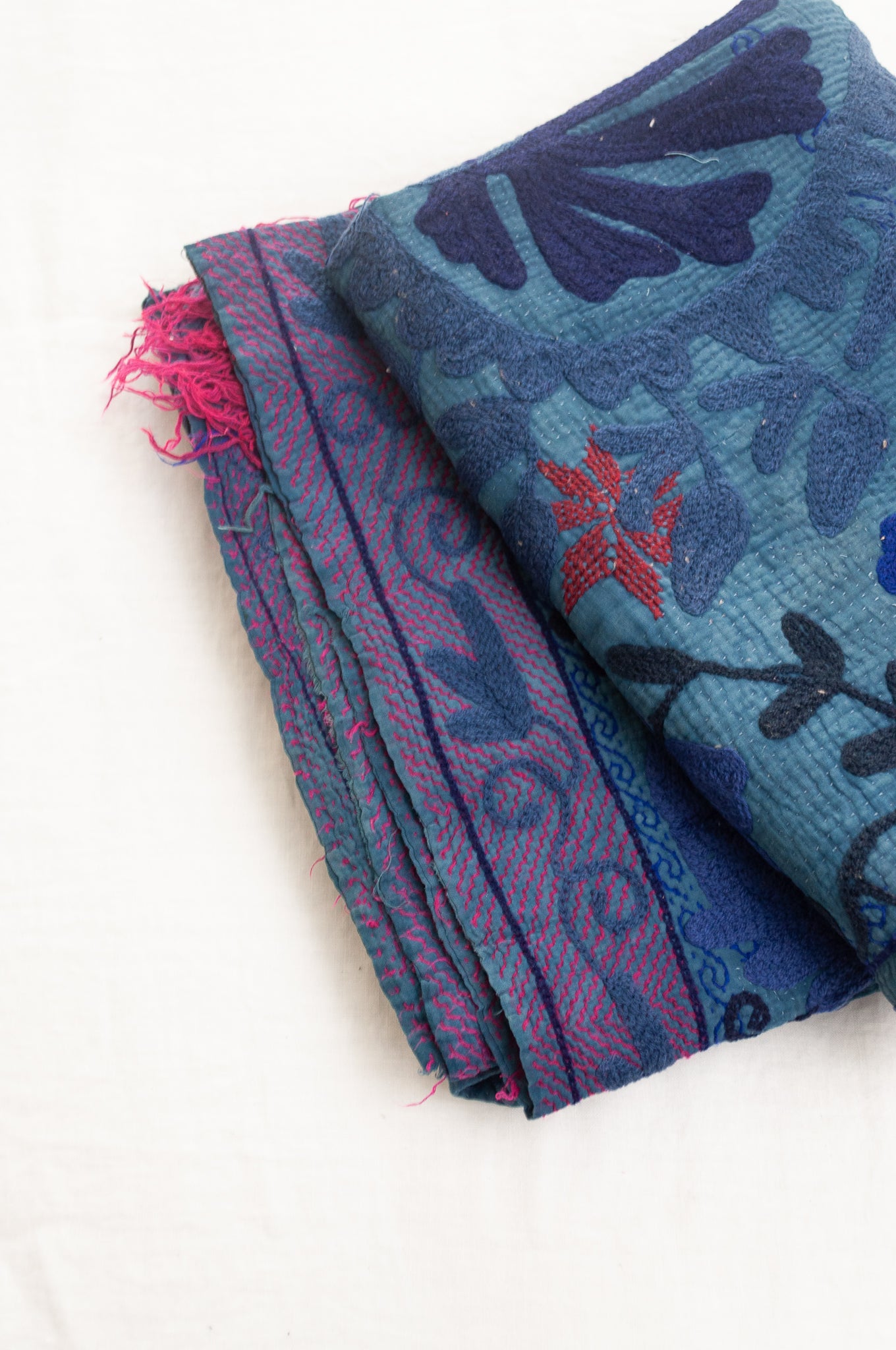 Vintage indigo kantha quilt embroidered Suzani style in shades of indigo with red highlights.