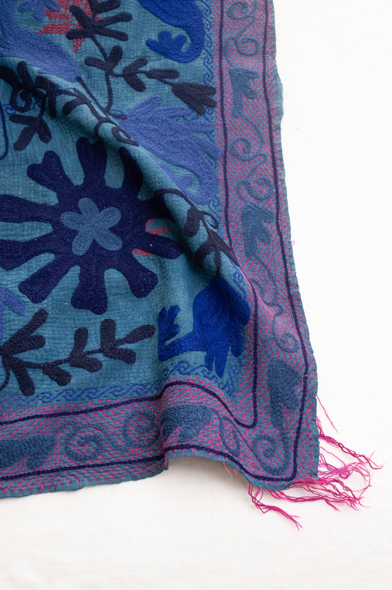 Vintage indigo kantha quilt embroidered Suzani style in shades of indigo with red highlights.