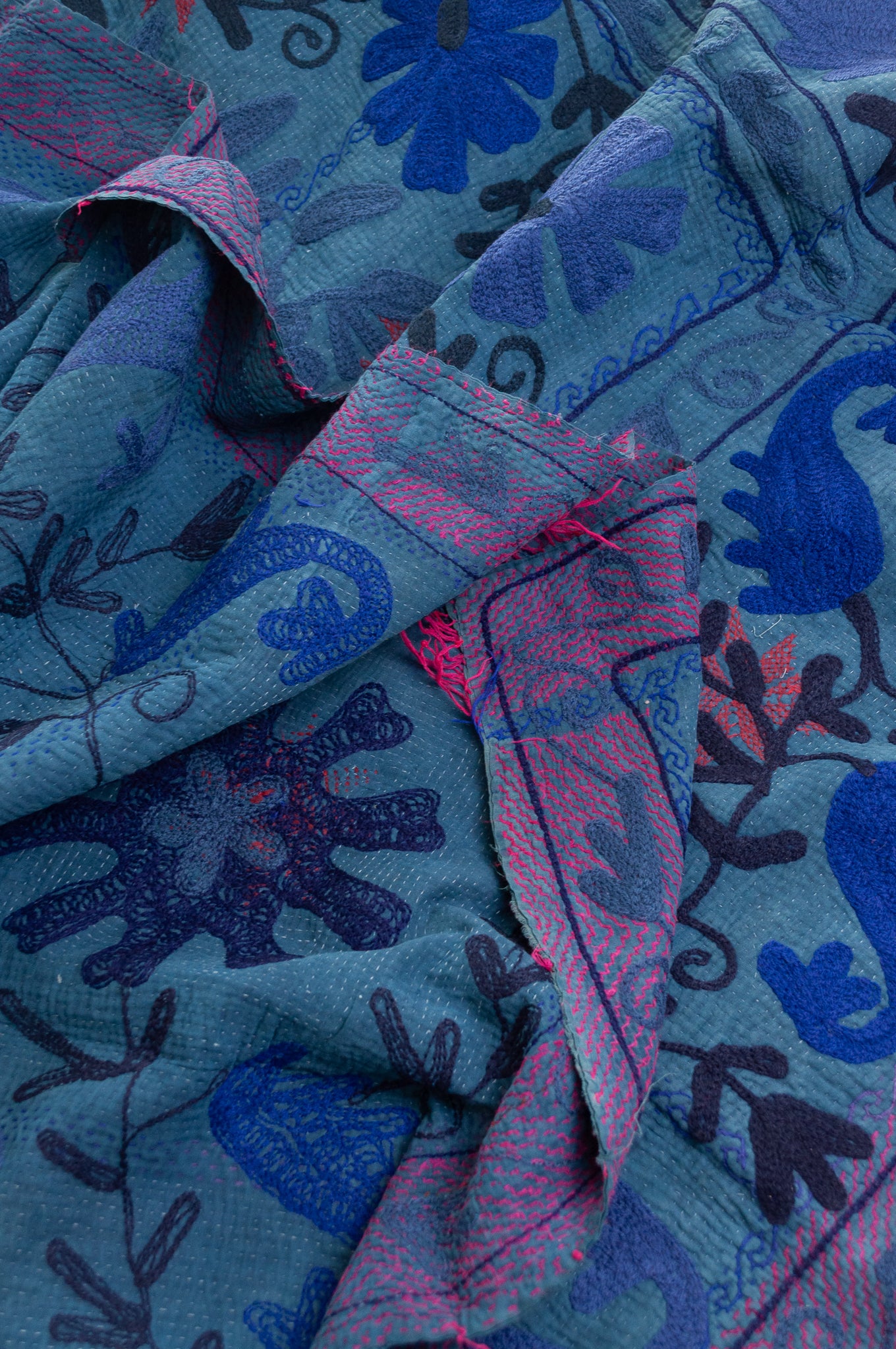 Vintage indigo kantha quilt embroidered Suzani style in shades of indigo with red highlights.