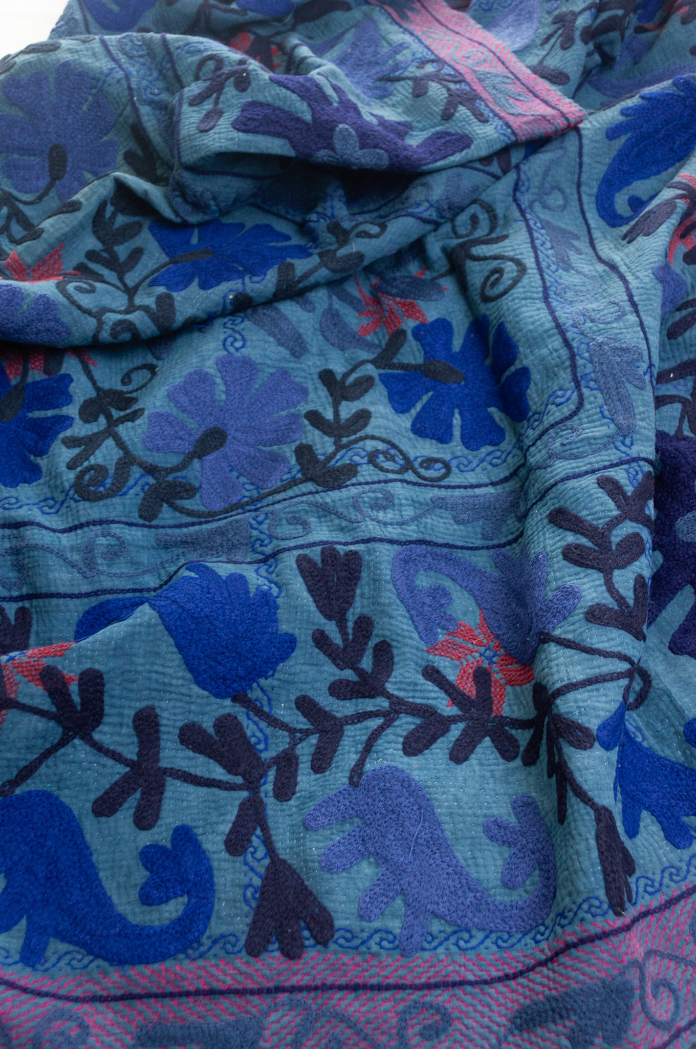 Vintage indigo kantha quilt embroidered Suzani style in shades of indigo with red highlights.