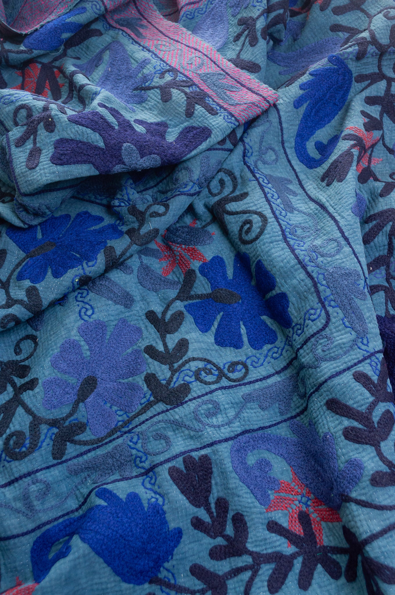 Vintage indigo kantha quilt embroidered Suzani style in shades of indigo with red highlights.