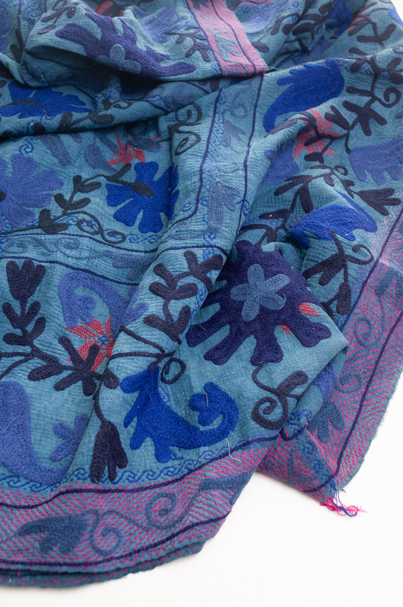 Vintage indigo kantha quilt embroidered Suzani style in shades of indigo with red highlights.