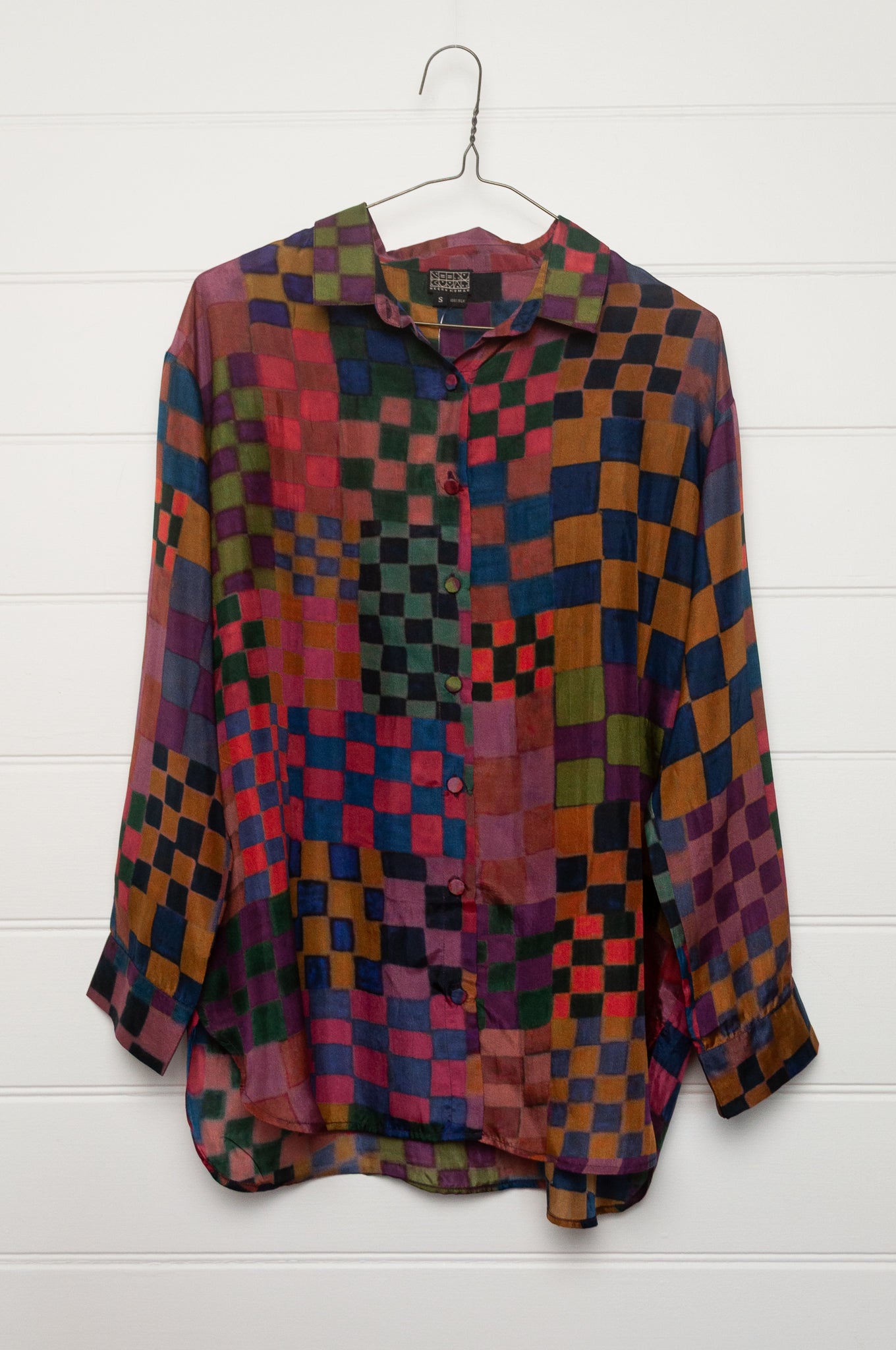 Neeru Kumar pure silk digital print button up long-sleeved blouse with a geometric checkerboard pattern in shades of burgundy, magenta, olive, blue, brown, and black.