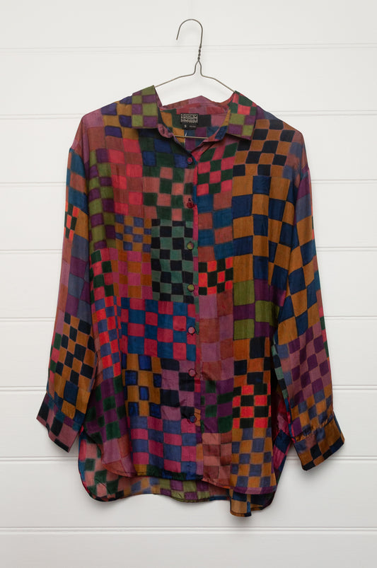 Neeru Kumar pure silk digital print button up long-sleeved blouse with a geometric checkerboard pattern in shades of burgundy, magenta, olive, blue, brown, and black.