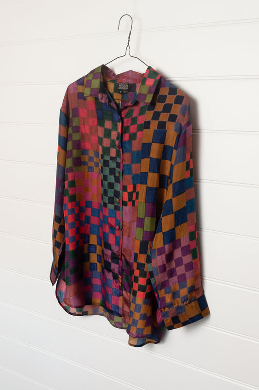 Neeru Kumar pure silk digital print button up long-sleeved blouse with a geometric checkerboard pattern in shades of burgundy, magenta, olive, blue, brown, and black.