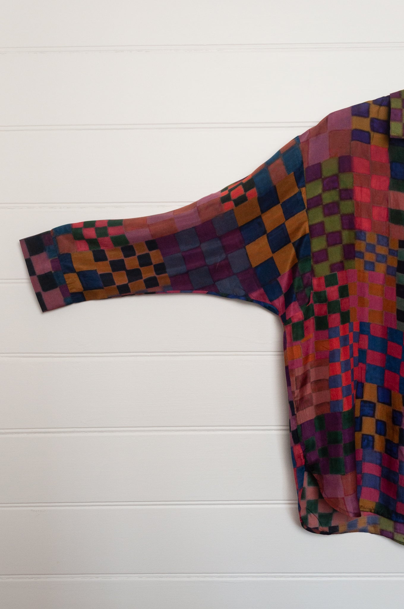 Neeru Kumar pure silk digital print button up long-sleeved blouse with a geometric checkerboard pattern in shades of burgundy, magenta, olive, blue, brown, and black.