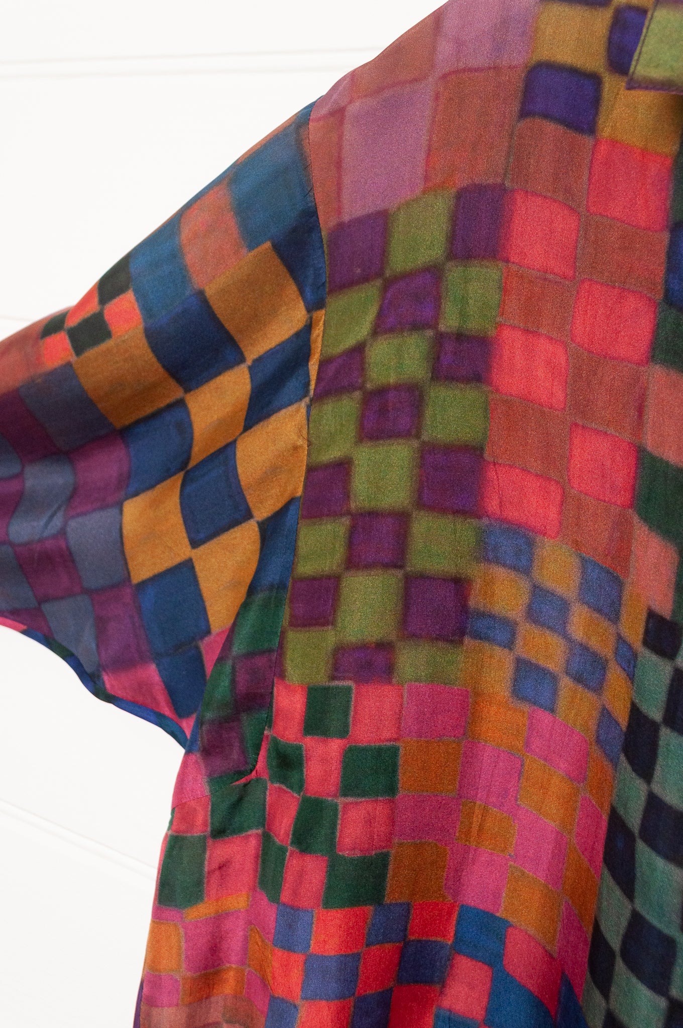 Neeru Kumar pure silk digital print button up long-sleeved blouse with a geometric checkerboard pattern in shades of burgundy, magenta, olive, blue, brown, and black.